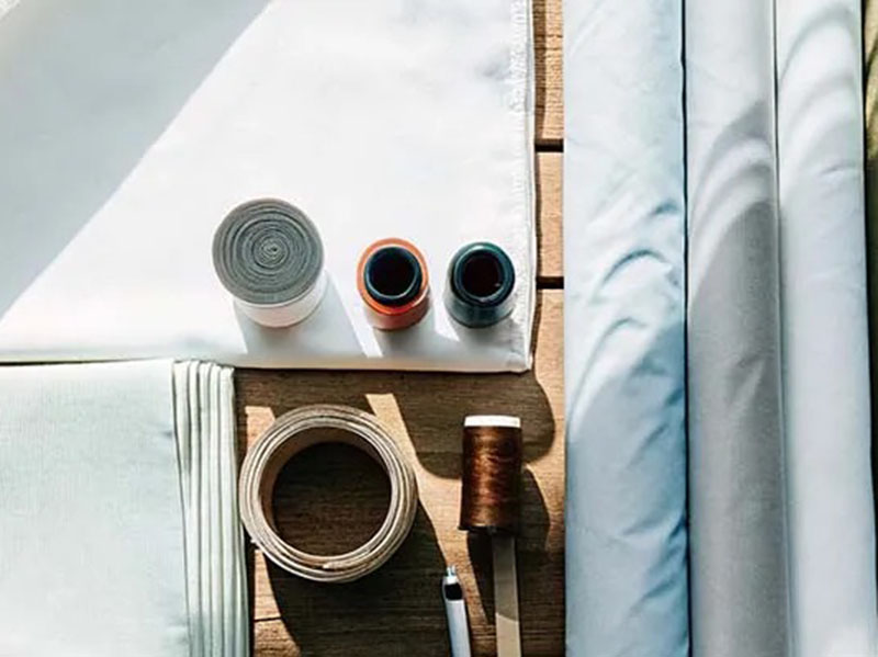Folded fabrics, thread spools, and sewing tools arranged on table