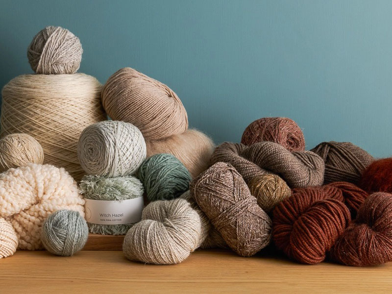 Assorted yarn skeins and thread balls displayed on wooden table