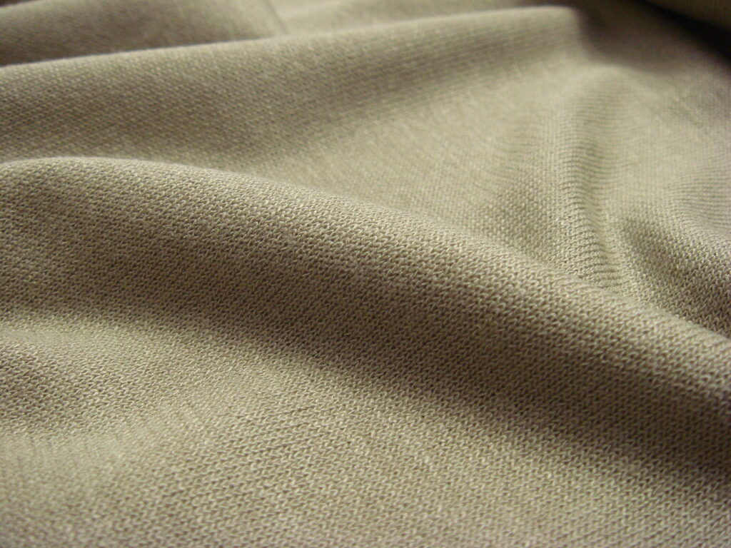 Close-up of beige knit fabric with soft folds and fine textured weave