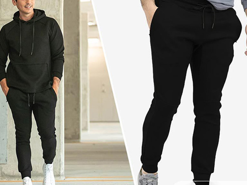 Man wearing black hoodie and slim black joggers with casual sneakers.