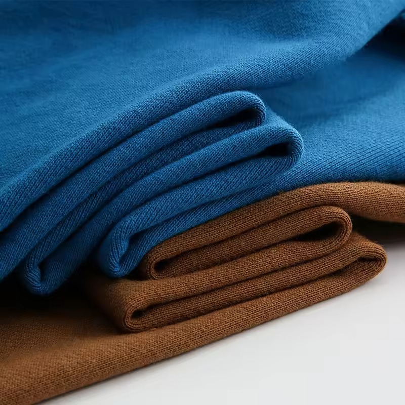 Folded knit fabrics in rich blue and brown tones, showing smooth soft texture.