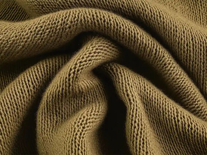 Close-up of brown knitted fabric with detailed texture and folds