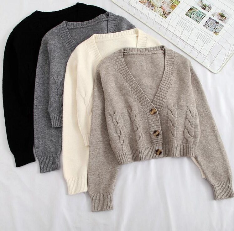 Four cable-knit V-neck cardigans neatly arranged on a flat surface.