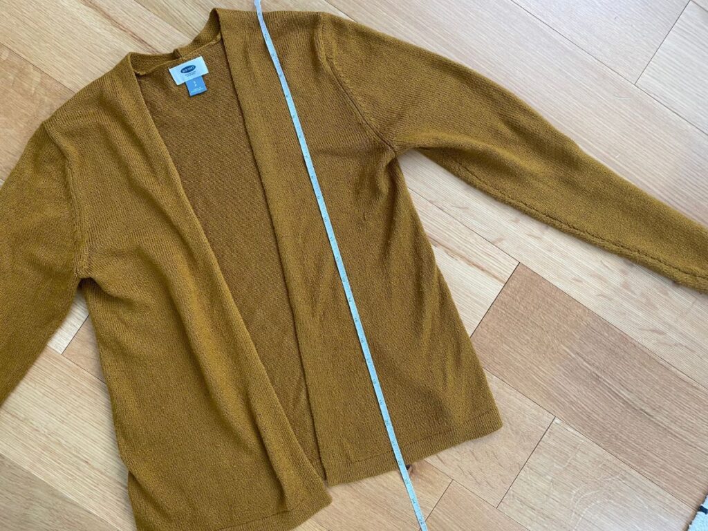 Brown open-front cardigan laid flat with measuring tape for size reference