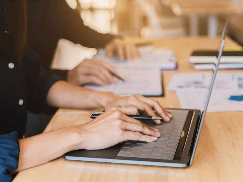 Professionals working at laptops and reviewing documents during office meeting