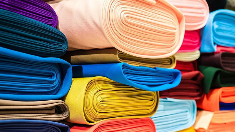 Brightly colored fabric rolls stacked tightly in a textile shop display
