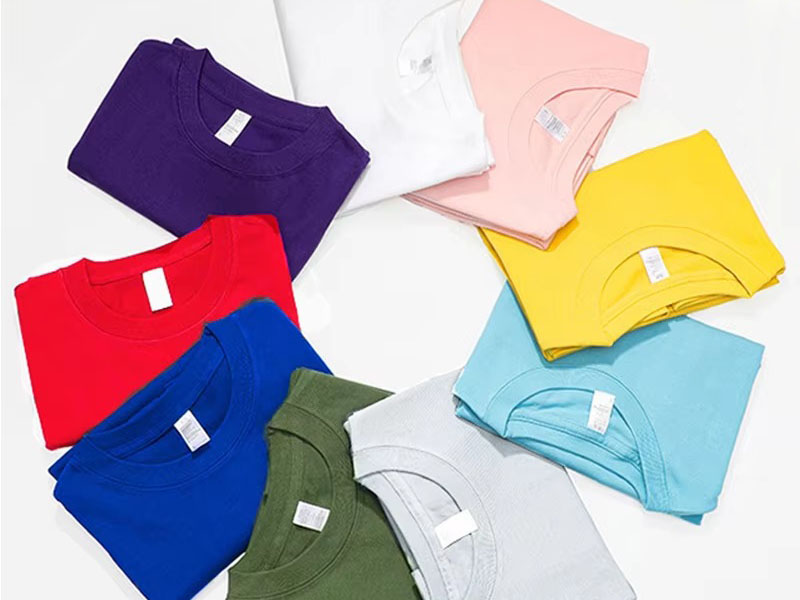 Folded colorful T-shirts arranged in circle on light background