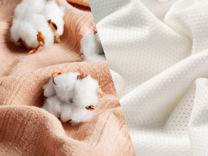 Cotton bolls on soft peach and white textured fabric close-up