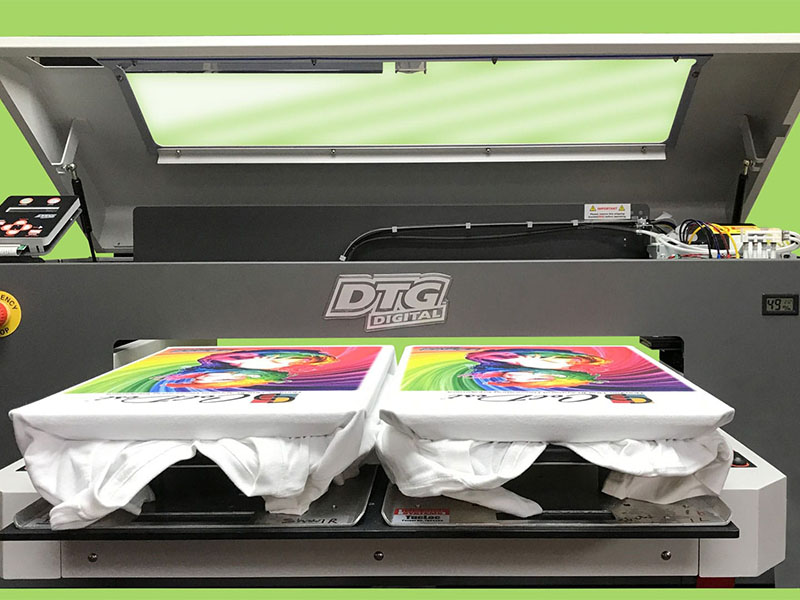 DTG printer producing colorful graphic designs on white T-shirts in print shop