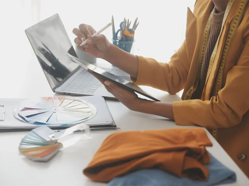 Fashion designer using tablet and color swatches at workspace 