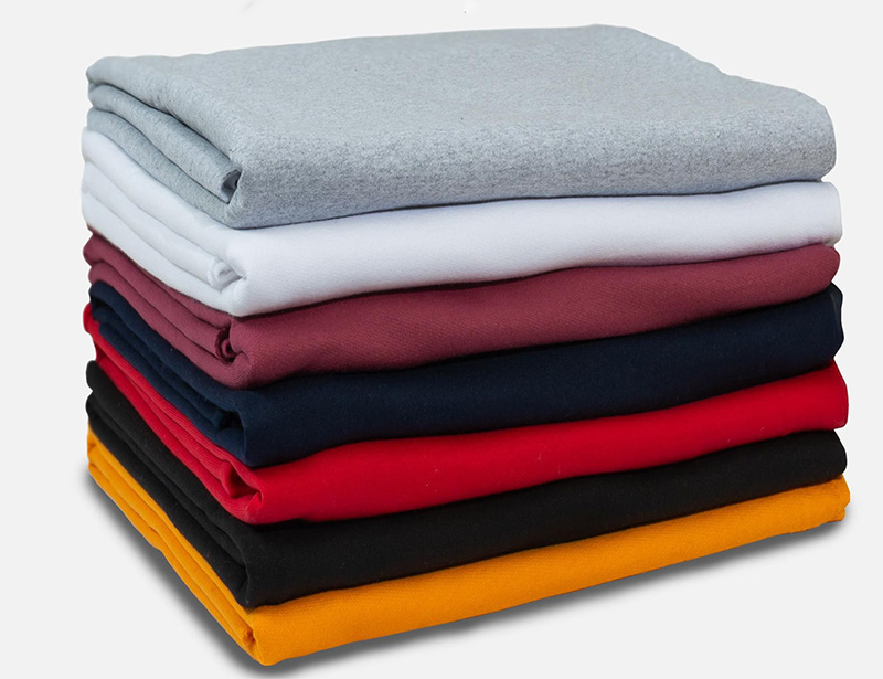 Stack of folded knit fabrics in gray, white, pink, navy, red, black, and mustard tones.