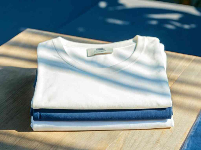 Folded white and blue T-shirts stacked neatly on wooden table