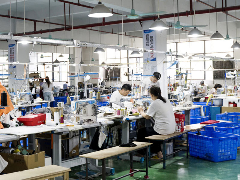 Busy garment factory floor with workers operating industrial sewing machines and production tables