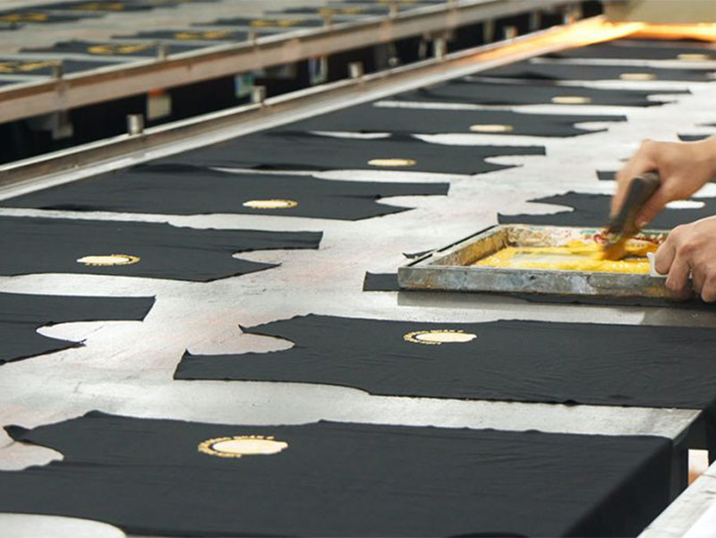 Black garment panels arranged on production table during screen printing process