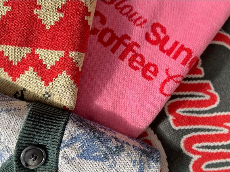 Folded knit garments with red, pink, and patterned graphic textile designs