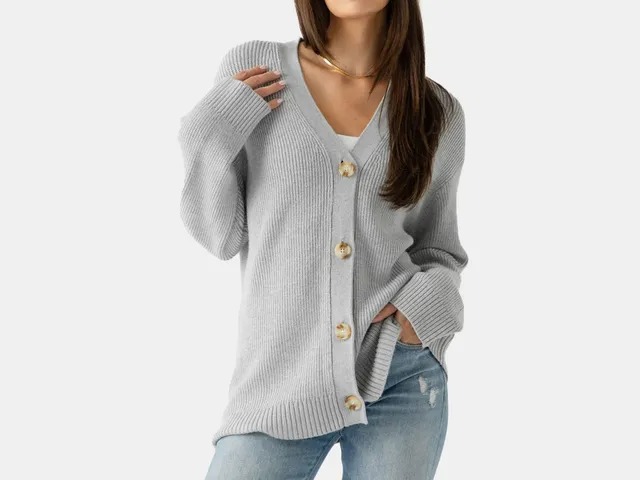 Woman wearing light gray ribbed cardigan with oversized fit and statement buttons