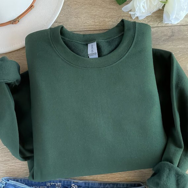 Folded forest green crewneck sweatshirt laid flat on wooden surface.