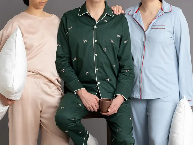 Three people wearing satin and cotton pajama sets in blush, green, and light blue.