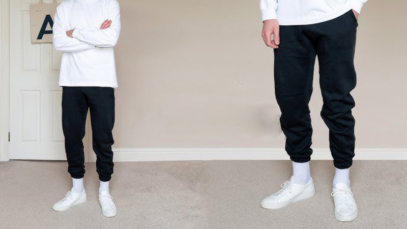 Man wearing black tapered joggers with white long-sleeve top and sneakers.