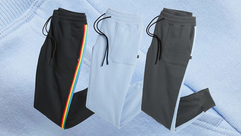 Three jogger pants in black, light blue, and gray with side stripe details and drawstring waists.