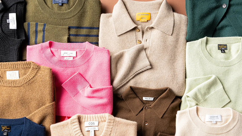 Folded knit sweaters and cardigans arranged in assorted colors and classic styles