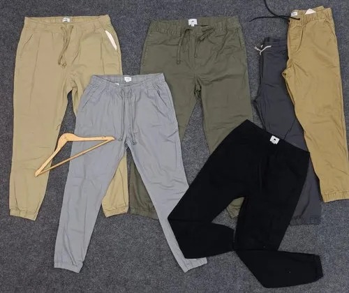Assorted jogger pants laid flat in beige, olive, gray, navy, and black colors.