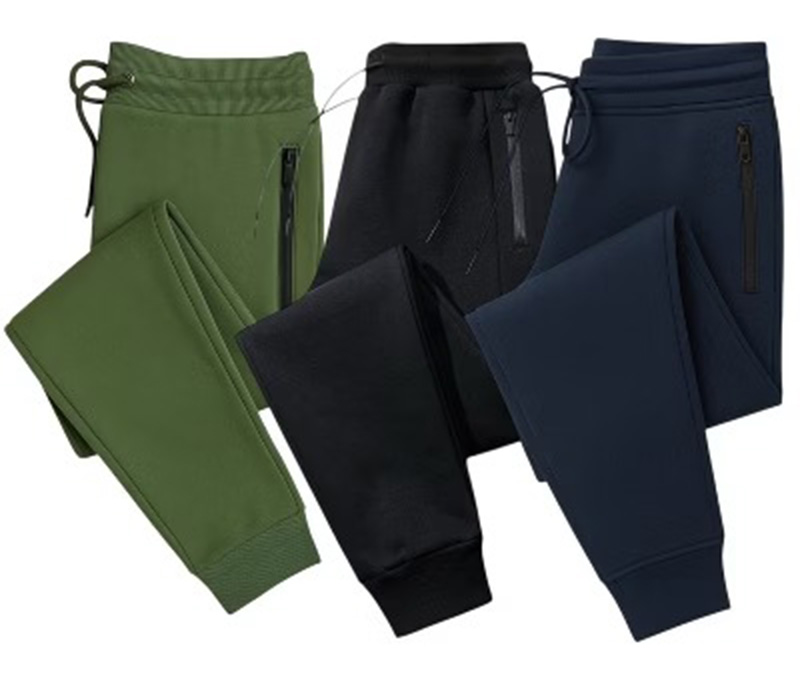 Three jogger pants shown in green, black, and navy with zipper pockets.