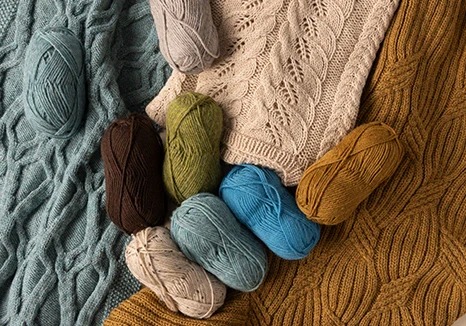 Knitted blankets and yarn skeins in soft neutral and earthy colors arranged together
