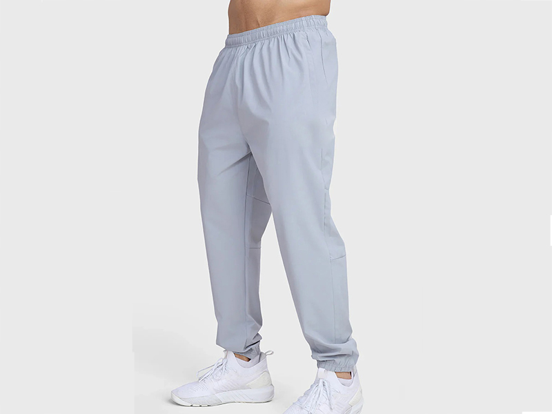 Men’s light gray jogger pants with elastic waistband and white sneakers.