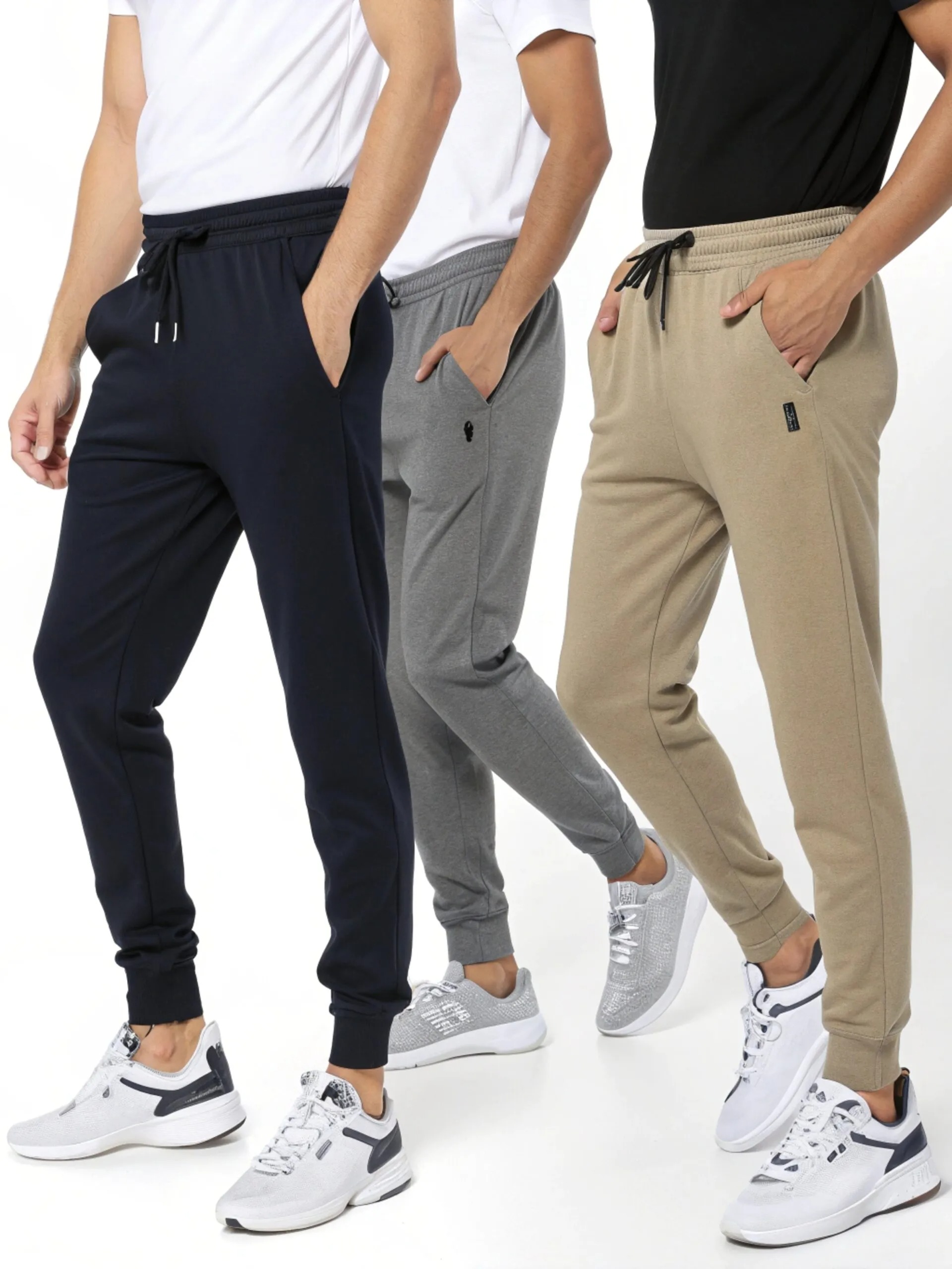 Three men wearing tapered jogger pants in navy, gray, and beige.
