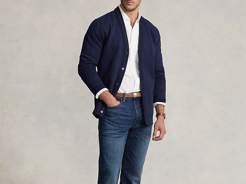 Man wearing navy shawl-collar cardigan over white shirt and blue jeans.
