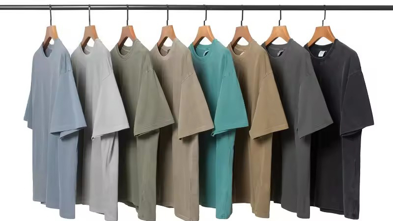 Solid-color T-shirts hanging on rack in muted neutral and cool tones