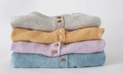 Stack of pastel knit cardigans folded neatly with visible button plackets