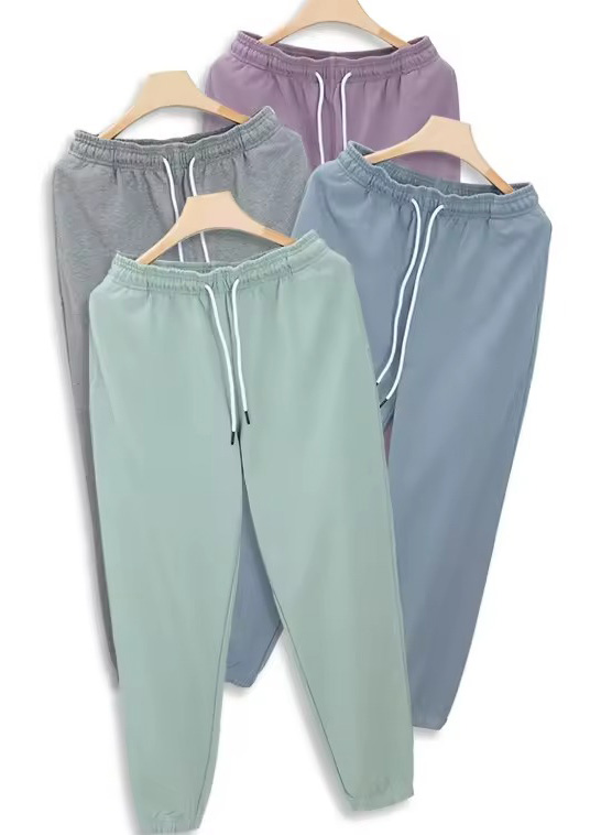 Four pastel jogger pants on hangers in mint, blue, gray, and lavender
