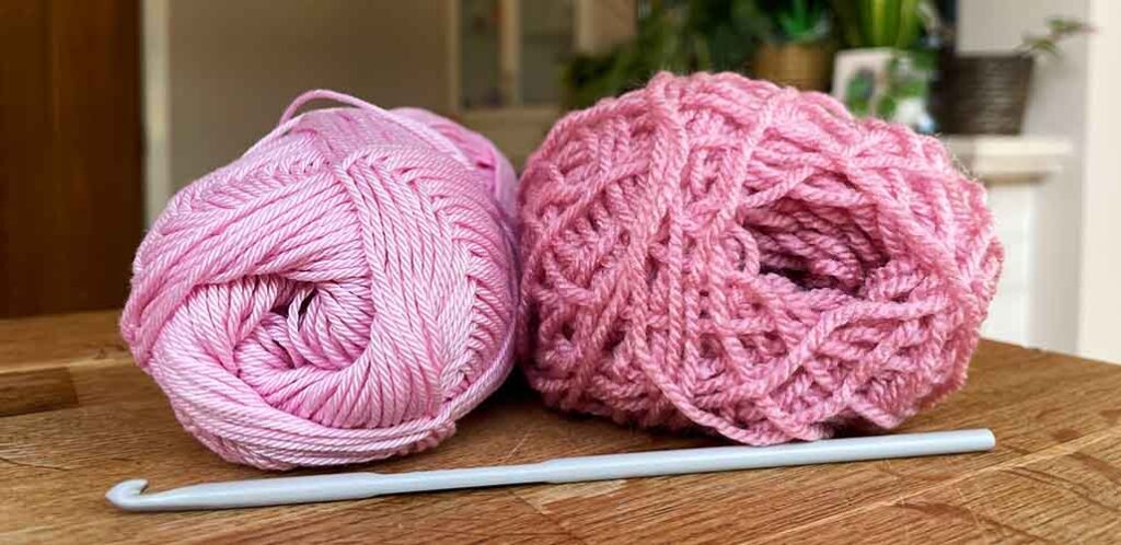 Two pink yarn balls placed on wooden table