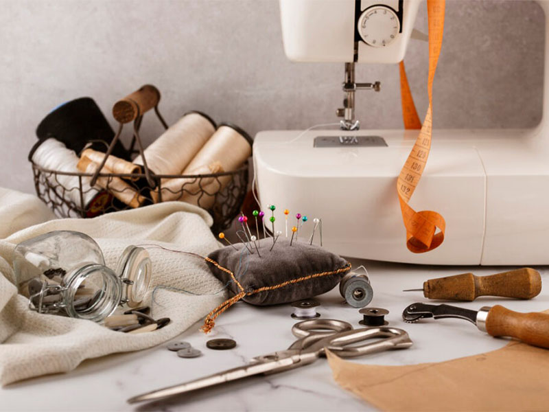 Sewing machine with scissors, thread spools, pins, and tailoring tools on workspace