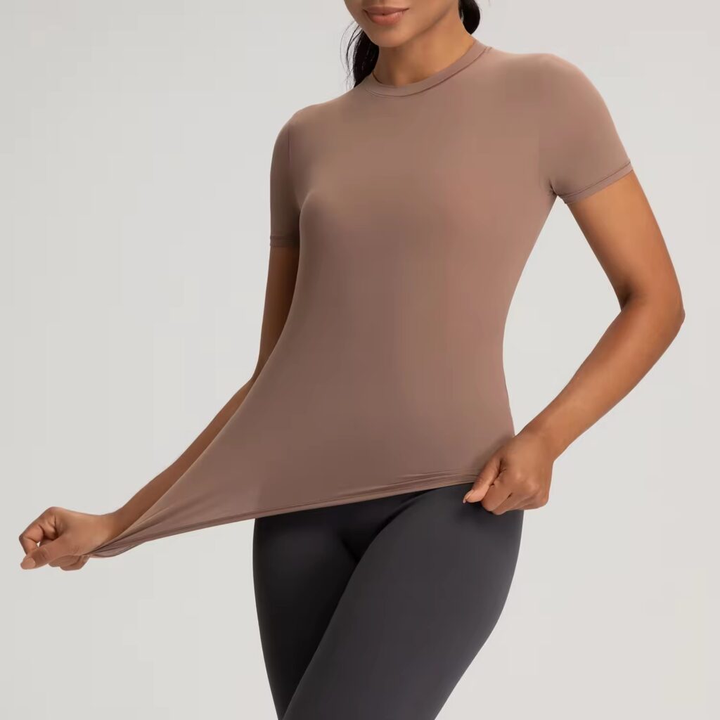 Woman stretching fitted taupe T-shirt to show soft, flexible fabric