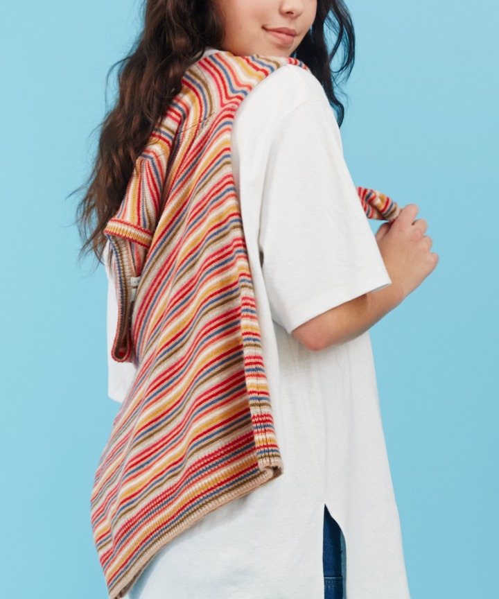 Woman wearing white T-shirt with colorful striped knit sweater draped over shoulder