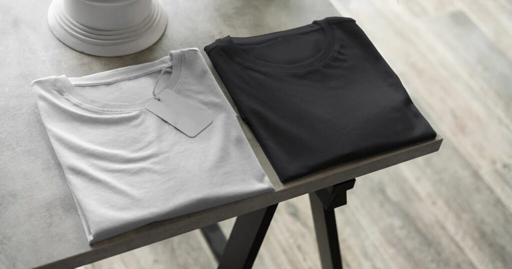 Folded white and black basic T-shirts displayed neatly on modern tabletop