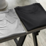 Folded white and black basic T-shirts displayed neatly on modern tabletop