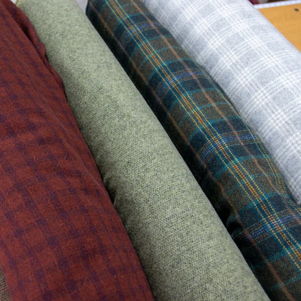 Four fabric rolls laid out side by side in different patterns and colors