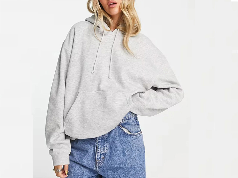 Woman wearing oversized gray hoodie styled casually with blue denim jeans.