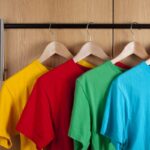 Colorful T-shirts hanging on wooden hangers against modern wardrobe doors