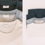 Folded crewneck sweatshirts in cream, gray, and dark green tones