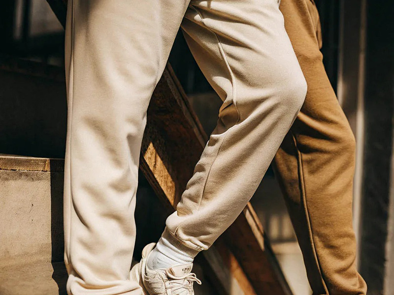 Two people wearing tapered jogger pants in cream and camel casual styles.