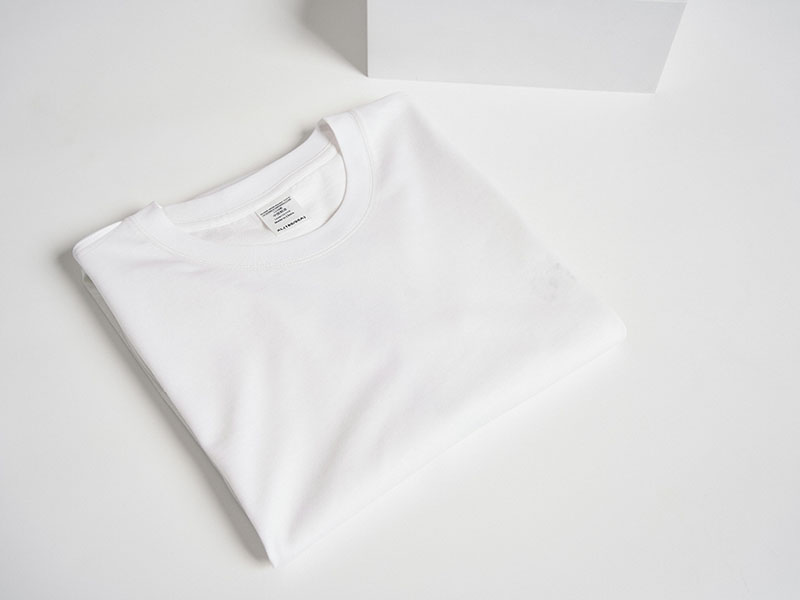 Folded plain white T-shirt placed on clean minimalist background