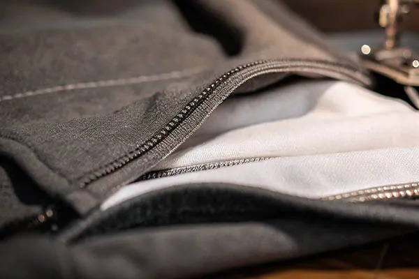 Close-up of zipper detail on layered gray and white garment fabrics