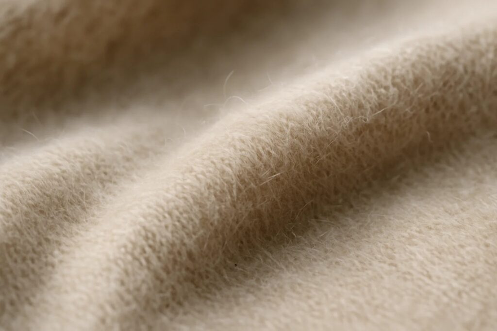 Close-up of cashmere fabric showing its fine fibers and fuzzy texture in gentle folds.