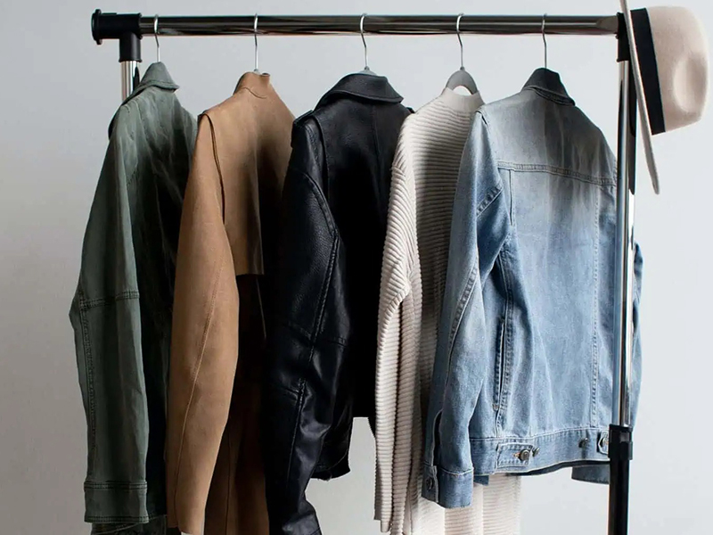 A clothing rack holding five jackets and a sweater, arranged from left to right