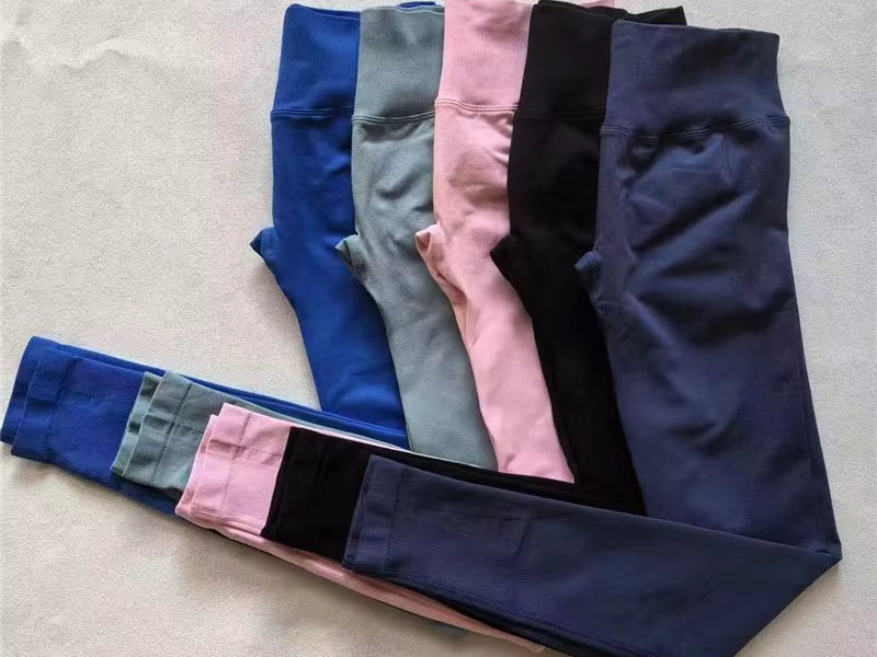 Colorful seamless high-waist yoga leggings folded on soft fabric background